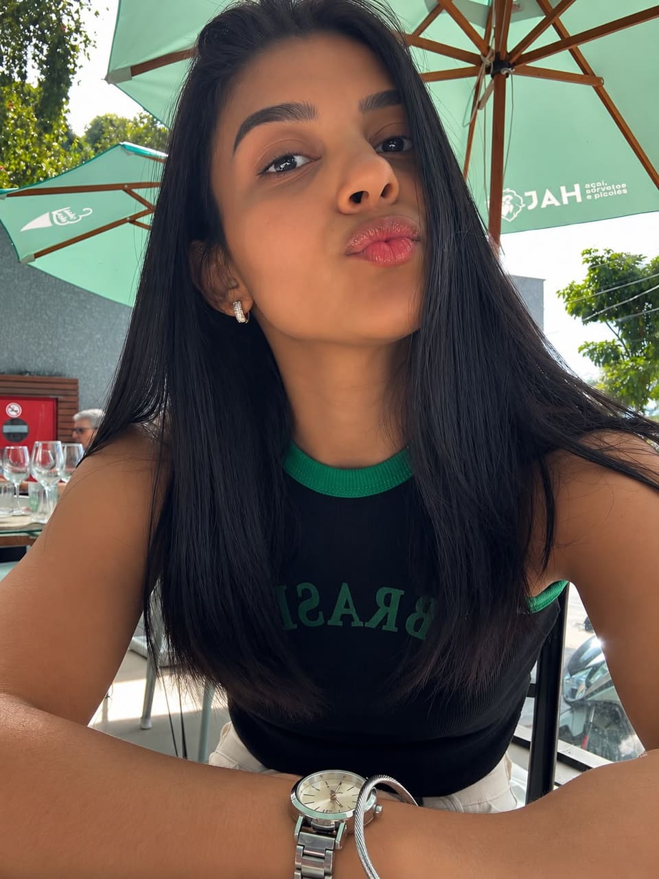 Retrato de Isabella de camiseta preta, num restaurante ao ar livre.