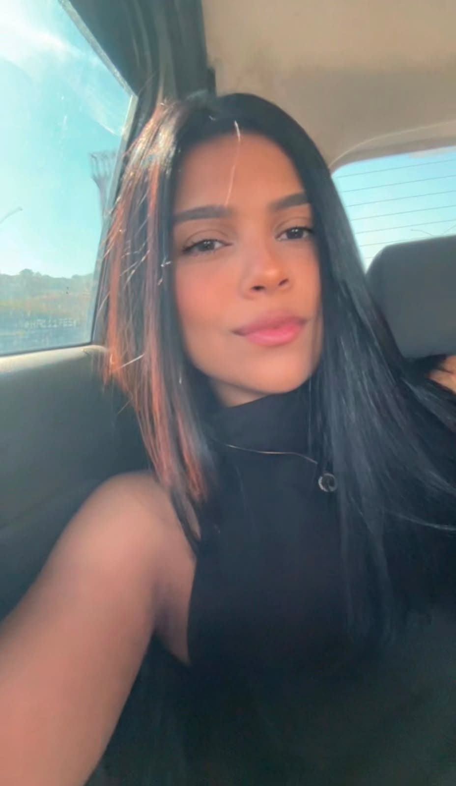 Selfie de Isabella no carro, de blusa preta.